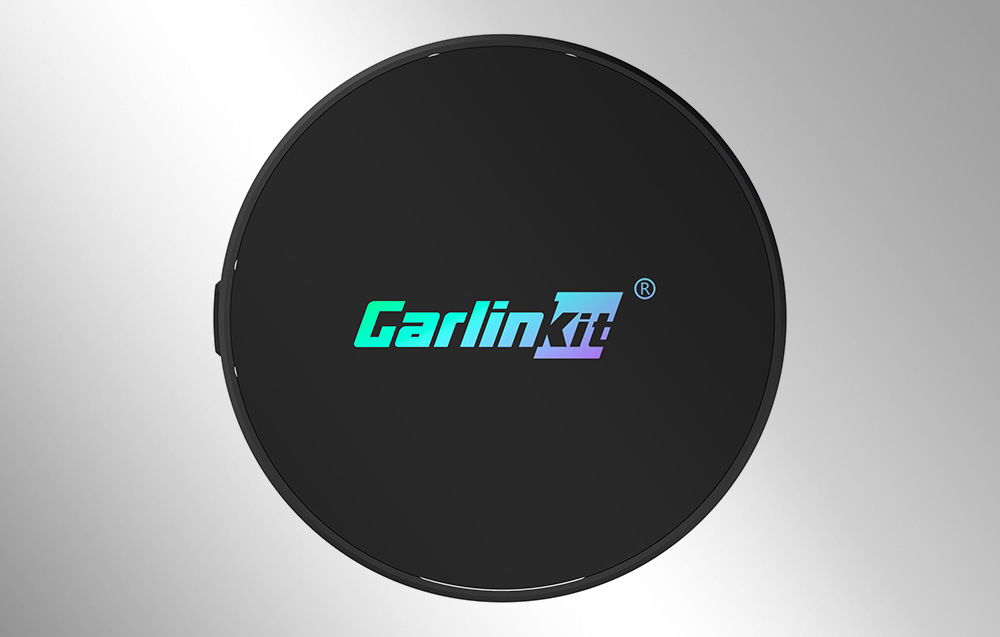 Μαύρος ασύρματος προσαρμογέας Carlinkit σε γκρι φόντο.